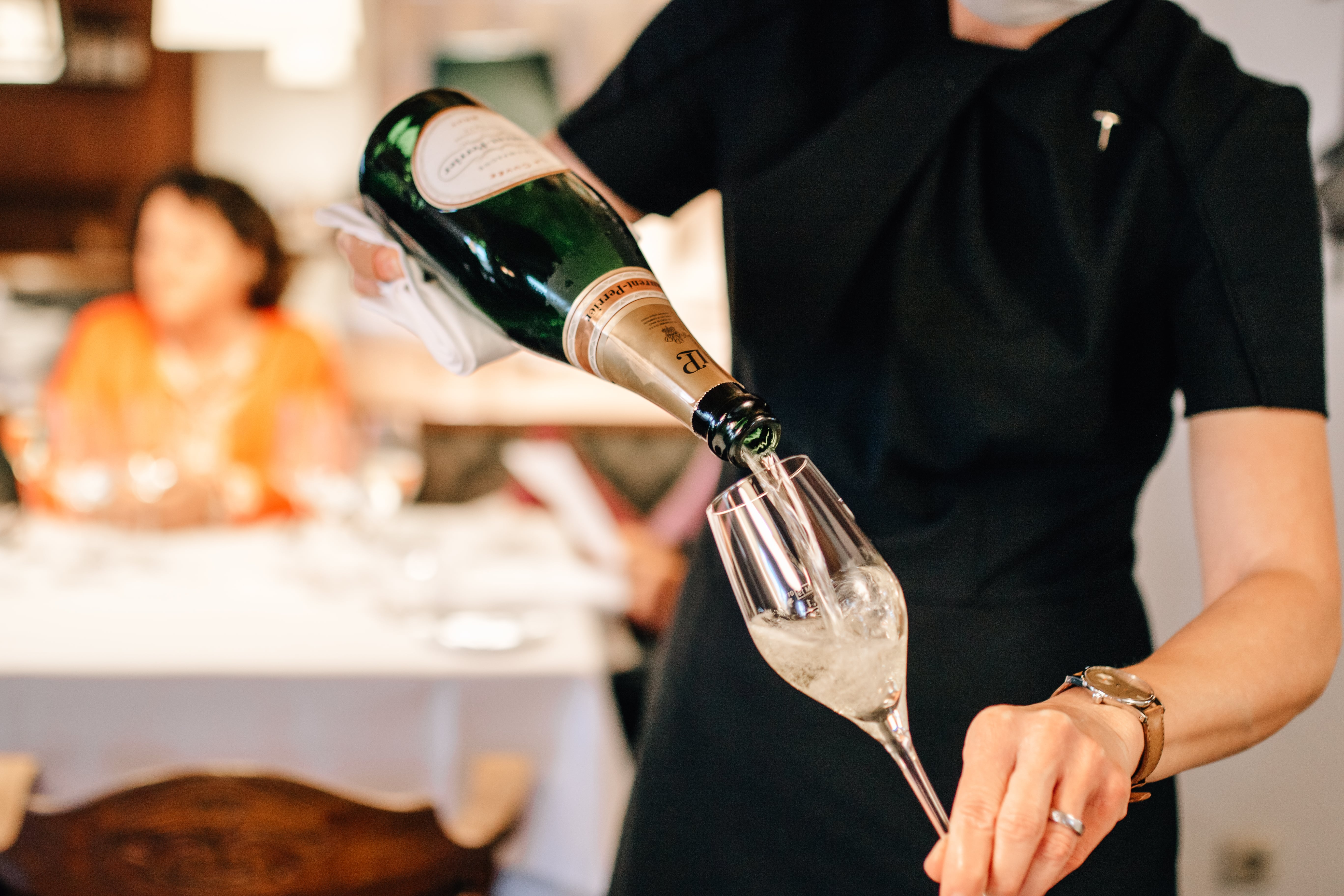 Eine Person, die Champagner in ein Glas gießt während eines Events im Restaurant